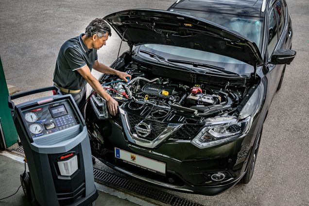 Mitarbeiter überprüft die Klimaanlagentechnik in der Motorhaube