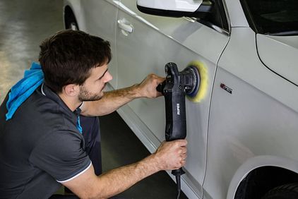 Mann poliert grauen PKW