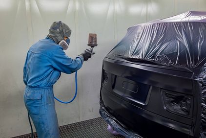 Mann im Schutzanzug lackiert Fahrzeug