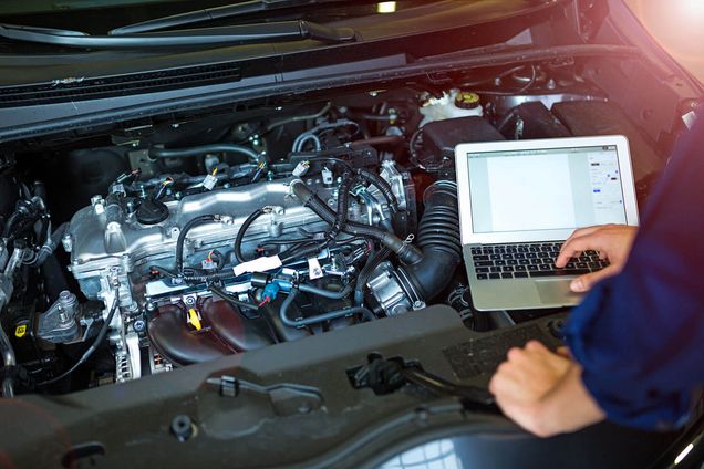 Techniker benutzt ein Diagnosesystem am Laptop auf einer Motorhaube